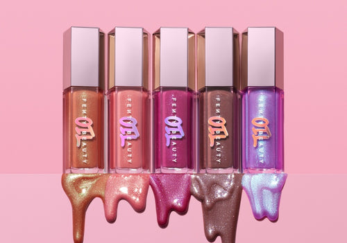 Gloss Bomb Oil new shade assortment with product dripping from the bottom on a pink background. Gloss Bomb Oil new shade assortment with product dripping from the bottom on a pink background.